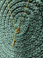 Geometric anti-tarnish gold pendant necklace on textured green background